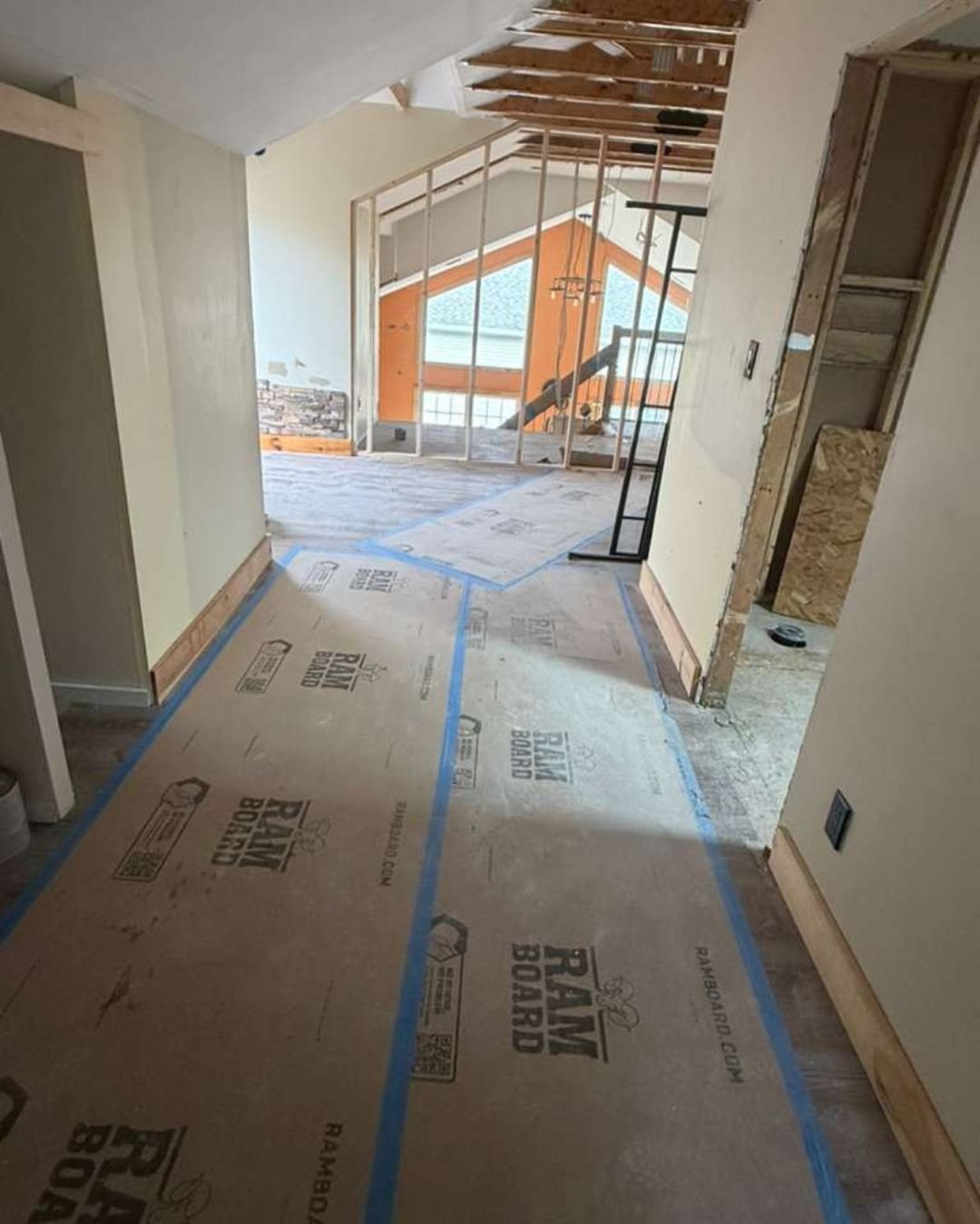 A clean hallway ready for renovation with a newly framed wall at the end and Ram Board temporary floor protection installed
