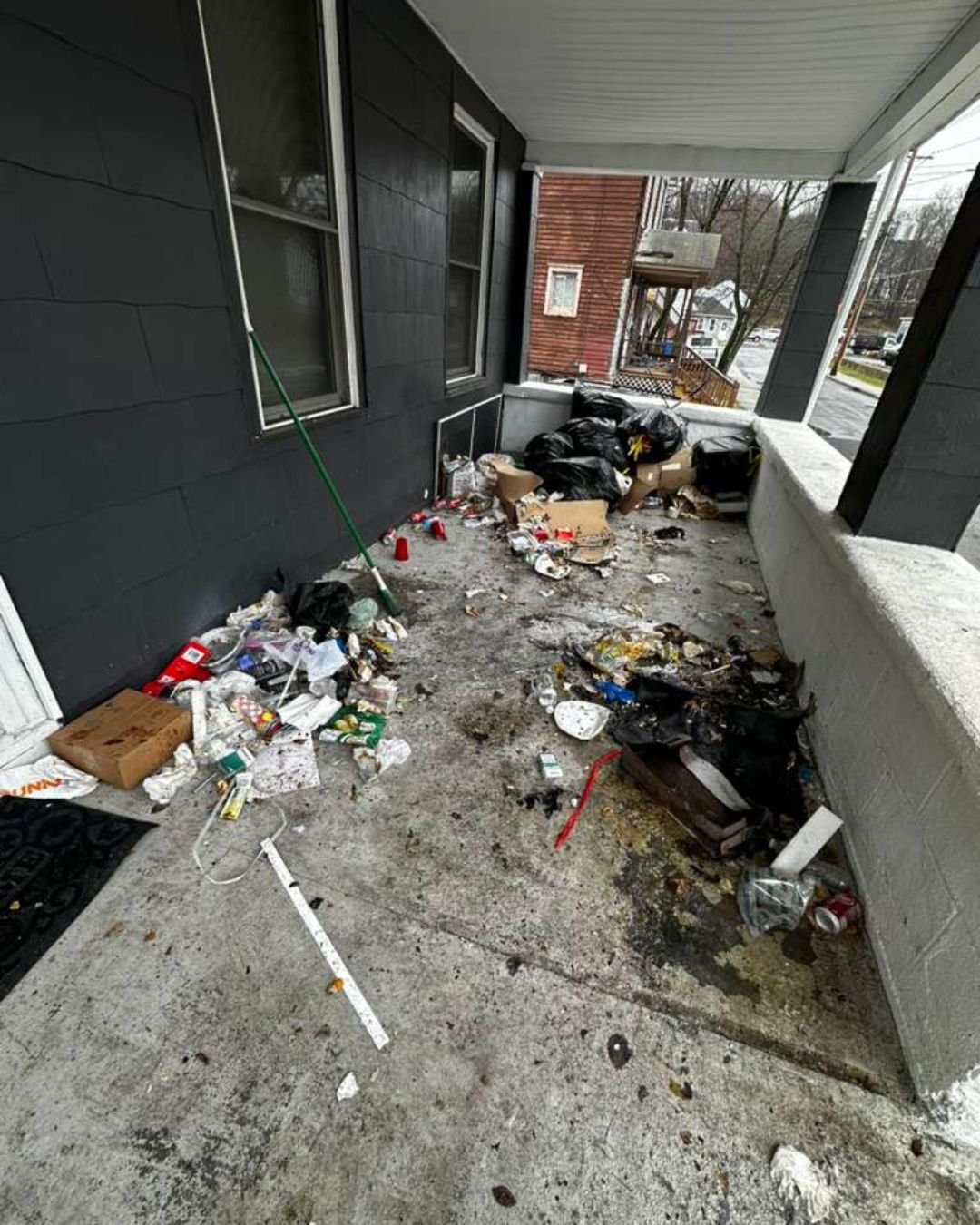 Close-up of a messy porch with scattered litter, food containers, and debris before a professional deep cleaning and junk removal