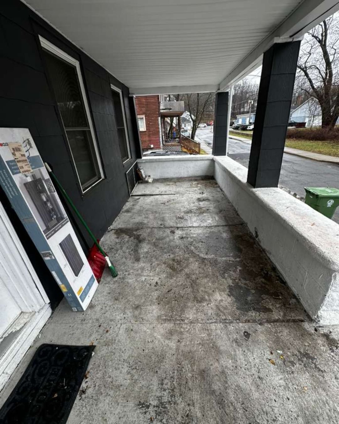 A completely cleared and swept concrete front porch, showing a dramatic difference after removing piles of household junk.